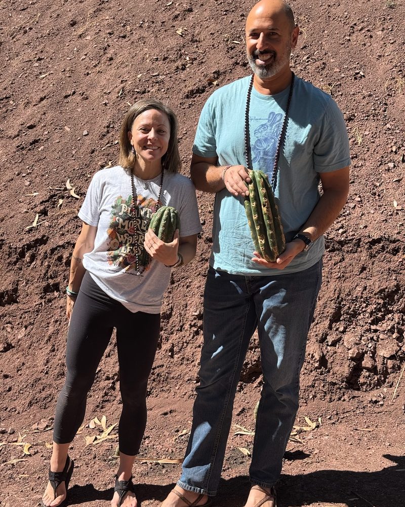 Two people standing on the terrace, each holding a Huachuma cutting ready to plant